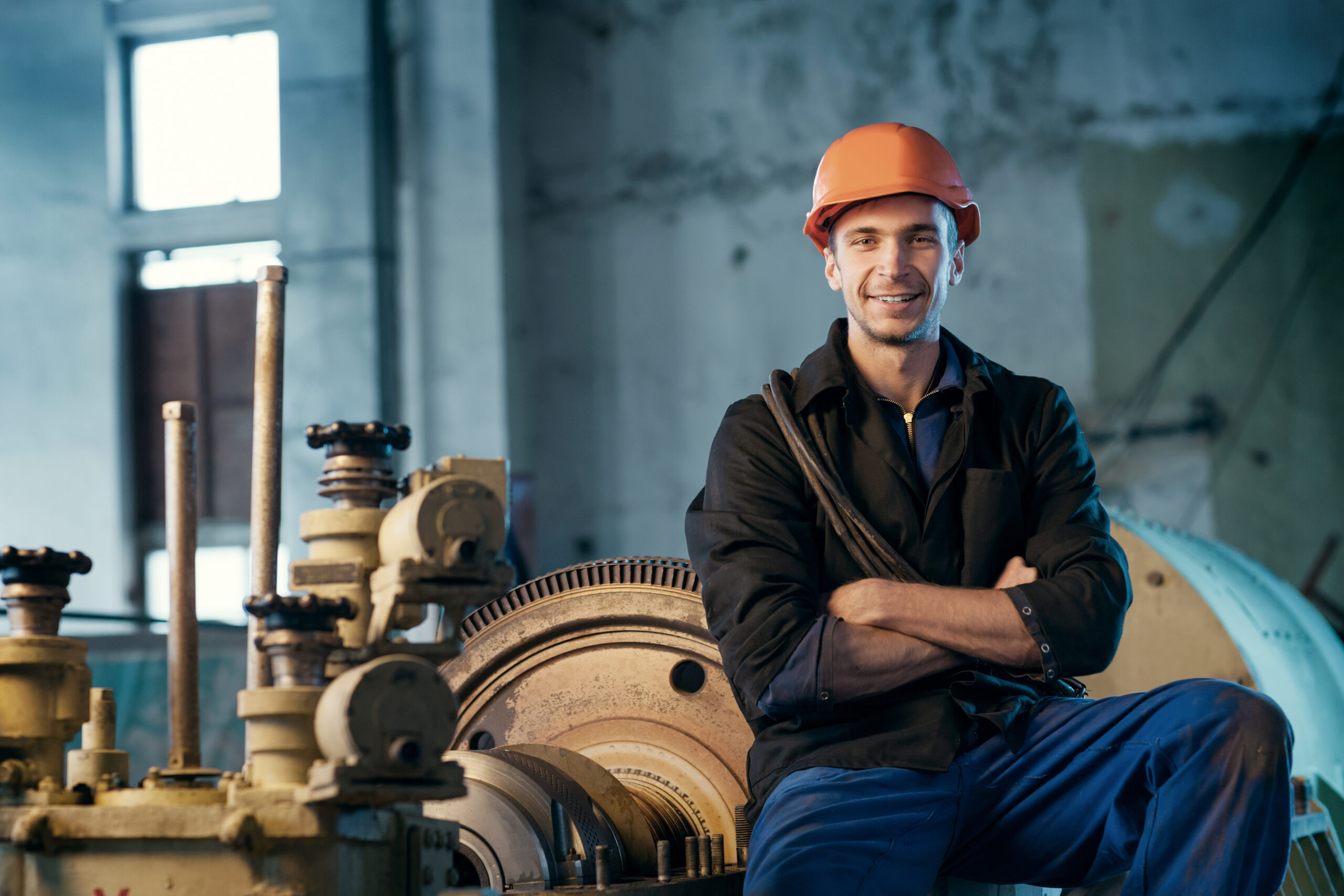 Portrait of a worker in the helmet near the steam turbine